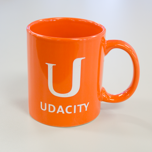 Orange mug with with Udacity and Udacity styalized 'U' logo